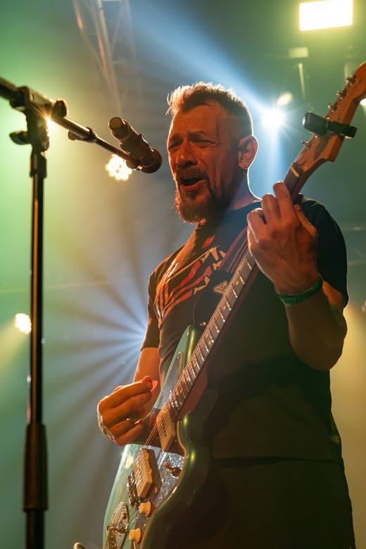 Juanjo Seguí sonriendo con el bajo entre haces de luz